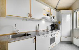 a kitchen with white cabinets and a sink at Holiday Home Spurvestræde in Dannemare