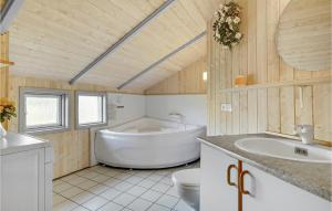 a bathroom with a tub and a toilet and a sink at Holiday Home Spurvestræde in Dannemare