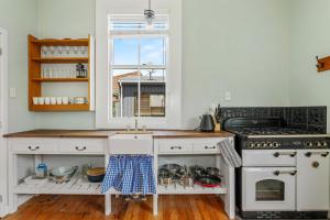 eine Küche mit einem Herd, einem Waschbecken und einem Fenster in der Unterkunft Central Heritage Villa in Rotorua