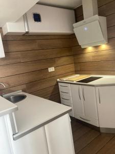 a kitchen with white cabinets and wooden walls at San José - ONGI ETORRI in Zumaia