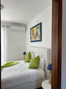 una camera bianca con letto e cuscini verdi di Casa Ana a Nazaré