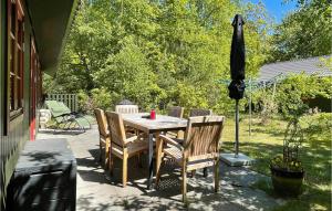 une table avec des chaises et un parasol sur une terrasse dans l'établissement 3 Bedroom Awesome Home In Nexø, à Strandby Gårde 22 autres photos