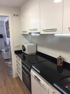 a kitchen with white cabinets and a black counter top at Apartamento nuevo Playa aislada Primera línea de playa in Cullera