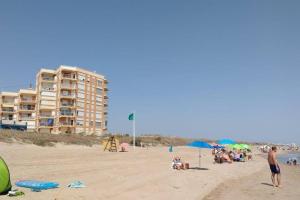 a group of people on a beach with a building at Apartamento nuevo Playa aislada Primera línea de playa in Cullera