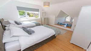 een slaapkamer met twee bedden en een raam bij Rooftops Braunton, Stylish Beach House - Fantastic Views - Hot Tub hire - Sleeps 8 in Braunton