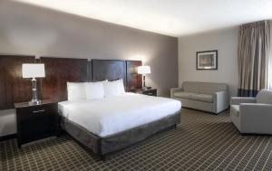 a hotel room with a large bed and a chair at Clarion Inn & Suites Miami International Airport in Miami