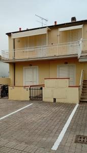 a building with a balcony and a parking lot at Casina al mare in Cecina