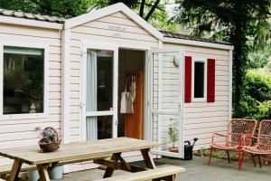 un capanno bianco con tavolo da picnic e sedie di Boshuisje Lou op de Veluwe a Hattemerbroek