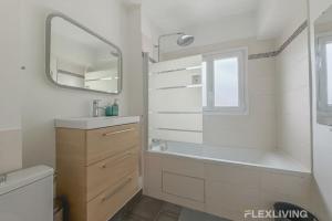 a bathroom with a tub and a sink and a mirror at Flexliving - room - Losserand in Paris +2 photos