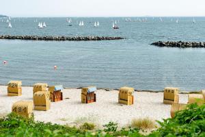 a group of chairs on the beach with boats in the water at Schilksee voraus! in Kiel