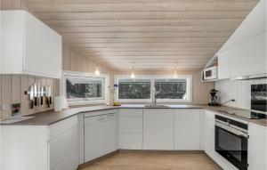 - une cuisine blanche avec des armoires et des fenêtres blanches dans l'établissement Holiday Home Mejsevej Nexø Ii, à Spidsegård