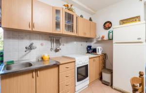 a kitchen with wooden cabinets and a white refrigerator at 3 Bedroom Nice Apartment In Jablanac in Jablanac +27 photos