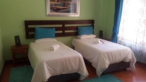 a bedroom with two beds with white sheets and blue pillows at Ikaze Guest House in Boksburg +45 photos