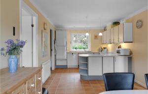 a kitchen with white cabinets and a vase of purple flowers at Holiday Home Stampen Vej Ii Hus in Rønne