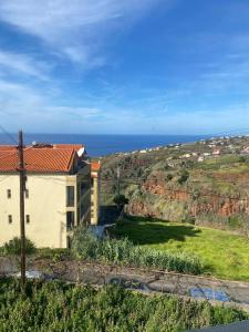 un edificio en una colina con el océano en el fondo en Sunset Star II With Sea View, en Calheta