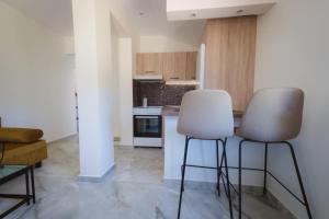 a kitchen with two white chairs and a counter at Armonia House in Dhíkella +20 photos