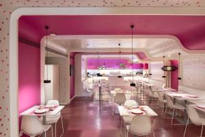 a restaurant with pink walls and white tables and chairs at Allegro Barcelona in Barcelona