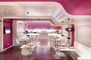 a restaurant with pink walls and white tables and chairs at Allegro Barcelona in Barcelona