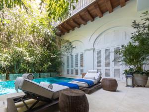 a patio with a pool with two beds and chairs at Hotel Casa Don Sancho By Mustique in Cartagena de Indias