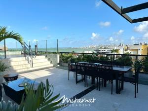 een patio met een tafel en stoelen en het strand bij Ozean Home Service - Jardim Oceania in Tambaú