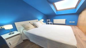 a blue bedroom with a bed and a window at Posada 3q blue sky in Posada de Llanes