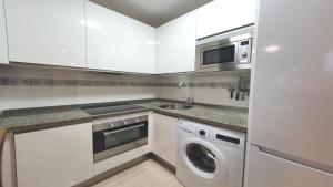 a white kitchen with a washer and a microwave at Posada 3q blue sky in Posada de Llanes