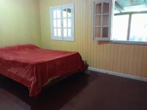 Un dormitorio con una cama roja con una ventana. en La Casita, en El Soberbio