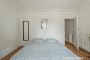une chambre avec un grand lit dans une pièce blanche dans l'établissement Flexliving - Room - Henri Sellier - Suresnes 92, à Suresnes