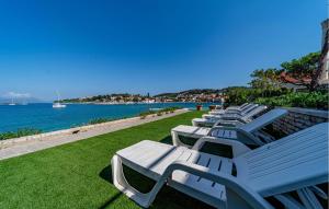 rząd białych ławek siedzących obok wody w obiekcie Apartment Koludrt Bb Croatia w mieście Lumbarda