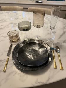 a black plate on a table with glasses and utensils at Modern House Family Retreat in Bar Harbor