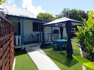 a patio with a table and an umbrella on the grass at Les Gîtes CocoCyrna - avec cuve d'eau in Sainte-Anne