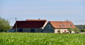 a large barn with a red roof in a field at De Reiziger in Stavele