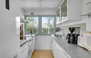 a kitchen with white counters and a large window at Holiday Home Kabbelejevej Væggerløse Ix in Marielyst