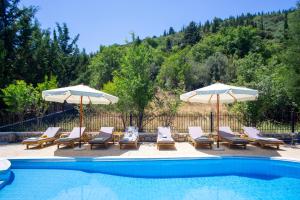 a group of chairs and umbrellas next to a pool at Apanema Mindfulness Resort Lefkada - ultra fast Starlink WiFi in 2025 in Asprogerakata