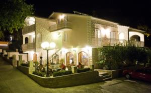 a building with people sitting in front of it at night at Wine Resort Adriatic Mikulic in Orebić