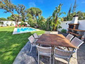 a patio with a wooden table and chairs and a pool at Villa Edén, Casa Rural lujo con Chimenea Piscina in Arcos de la Frontera