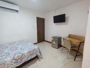 a bedroom with a bed and a desk with a television at Confortable y Central Habitación a 1 cuadra de la playa in San Andrés