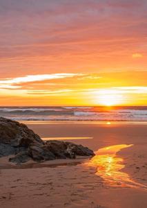 una puesta de sol en una playa con una roca en la arena en Willow Bungalow Quiet and secluded, en Carbis Bay