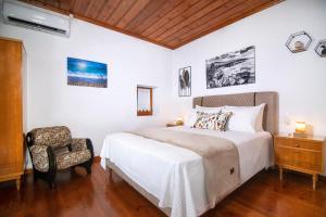 ein weißes Schlafzimmer mit einem Bett und einem Stuhl in der Unterkunft Mikros Paradisos Pelion in Áyios Vlásios