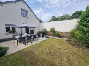 eine Terrasse mit einem Tisch und einem Sonnenschirm im Hof in der Unterkunft Échappée belle en baie de Somme in Saint-Quentin-Lamotte-Croix-au-Bailly