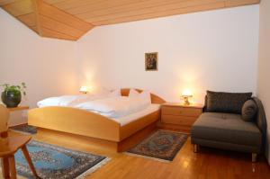 a bedroom with a bed and a couch and a chair at Residence Granvara in Ortisei