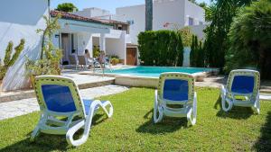 three lawn chairs sitting in the grass near a swimming pool at Landhaus mit Garten, Sonnenterrasse sowie überdachter Terrasse und Pool in Strandnähe in Cala Ratjada
