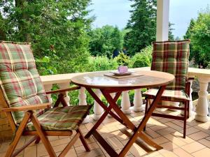 two chairs and a wooden table on a porch at Haus am See mit Kamin in Mecklenburg in Cammin