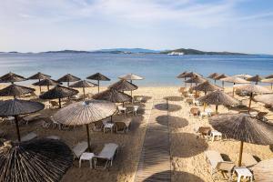 a beach with chairs and umbrellas and the water at Alexandros Palace in Ouranoupoli