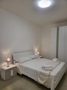 a white bedroom with a large bed and a lamp at Partenope in Termoli