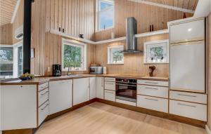 a kitchen with white cabinets and wooden walls at Holiday Home Tranebærvej Tarm Ix in Hemmet