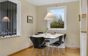 a dining room with a white table and chairs at Awesome Home In Væggerløse With Kitchen in Marielyst