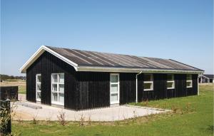 a black building with white windows on a field at Four-Bedroom Holiday Home In Lokken in Løkken