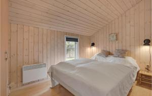 a bedroom with a white bed in a room with wooden walls at Holiday Home Ringvejen X in Lakolk +16 photos