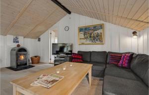 a living room with a couch and a table and a fireplace at Holiday Home Ringvejen X in Lakolk